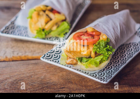 Griechische Gyros in pita Brot auf einem hölzernen Hintergrund gewickelt. Griechische küche Konzept. Stockfoto