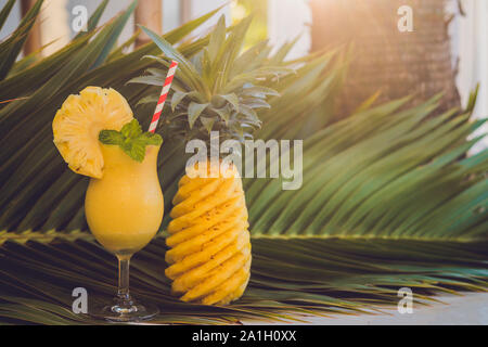 Ananas und Ananas smoothies vor dem Hintergrund einer Filiale einer Palme. Stockfoto