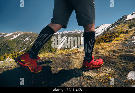 Nahaufnahme von Wanderer Beine in rote Schuhe Klettern in den Bergen und blauer Himmel. Gesunde Lebensweise. Outdoor Travel Concept. Stockfoto