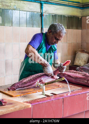 Male, Malediven - November 16, 2017: der Mann, der die großen Thunfischen für den Verkauf auf dem Fischmarkt in der Stadt und der Insel Male, die Hauptstadt der Malediven. Stockfoto