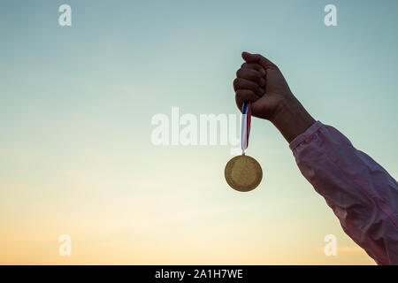 Hand hält eine Goldmünze, hohe und Sieg. Stockfoto