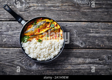 Gelbes Curry, Panang Curry mit gegrillten Saba Makrele Fisch mit gedämpftem Langkornreis in einer Pfanne auf einem rustikalen Holztisch, Ansicht von oben, Stockfoto