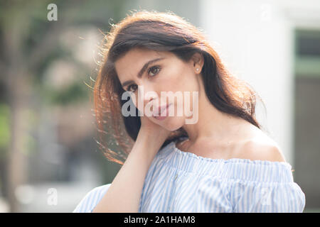 Schüchtern, aber flirty brunette stopfte ihr Haar hinter die Ohren, Nahaufnahme, sonnig warmen Tag Stockfoto