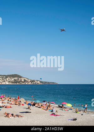 Menschen Sonnenbaden am Strand wie ein Flugzeug über Fliegen in Nizza, Frankreich, Europa landen Stockfoto