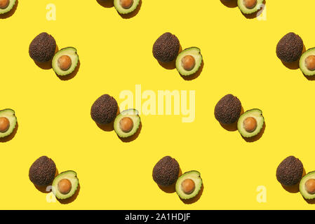 Avocado Muster aus ganze und halbe Avocado auf gelben Hintergrund. Stockfoto