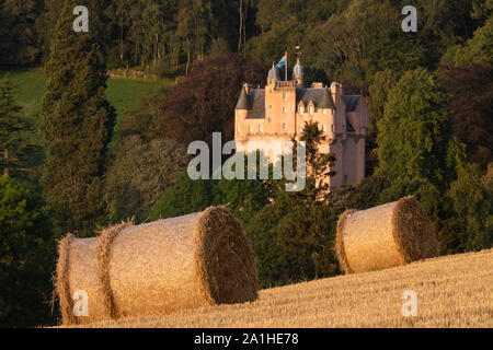 Ein Blick auf Craigievar Castle Sitzen im Wald mit Strohballen in einem Feld der Schnitthöhe Stockfoto