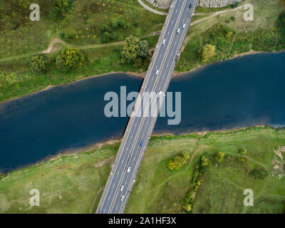 Landschaft von einer asphaltierten Straße mit Autos. Blick von oben auf die Brücke und Der blaue Fluss. Sommer Fotografie mit Bird's Eye View. Stockfoto