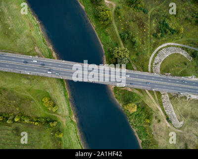 Landschaft von einer asphaltierten Straße mit Autos. Blick von oben auf die Brücke und Der blaue Fluss. Sommer Fotografie mit Bird's Eye View. Stockfoto