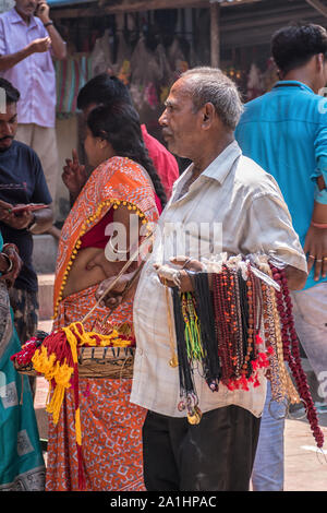 Ein Mann, die Blumen, rudraksha Mala, Roter Faden oder Heiligen Threads, Gott Medaillon, Girlanden an Baba Taraknath Tempel, ein Hindu Tempel Sh zu Gott Stockfoto