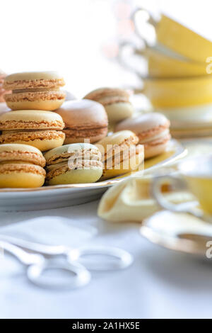 Selektiver Fokus einer Platte voller Macarons in der Nähe der hübschen gelben Tassen im Hintergrund vertikale Bilder mit Kopieren und Platz für Text-overlay Stockfoto