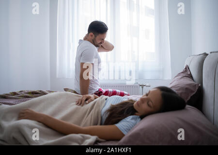 Junges Paar ist das Aufwachen am Morgen. Man hat Schmerzen im Nacken. Stockfoto