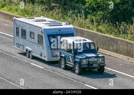 2001 Blue Land Rover Defender 90 TD5 mit Schnorchelauslass, Abschleppen Buccaner Caravan; UK Verkehr, Transport, modern, Limousinen, Richtung Süden auf der Autobahn M6 mit 3 Fahrspuren. Stockfoto