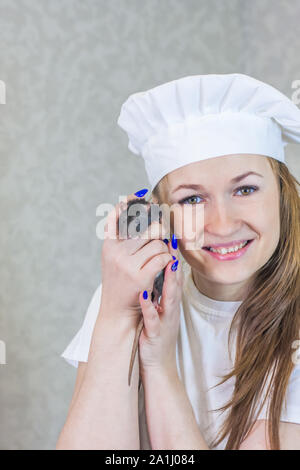 Küche Konzept. Eine Frau in einer Köchin kostüm hält eine Ratte in die Arme. Der Mann mit der Maus posieren. Stockfoto