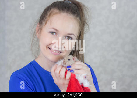 Das Konzept der beliebtesten Haustiere. Das Mädchen hält die Maus und lächelt. Schöne Frau mit einer Maus posieren. Stockfoto