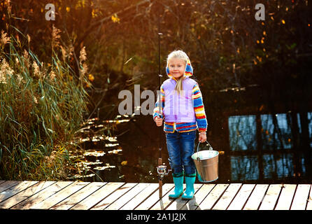 Einsame Kind Angeln aus Holz- Dock auf See. Stockfoto