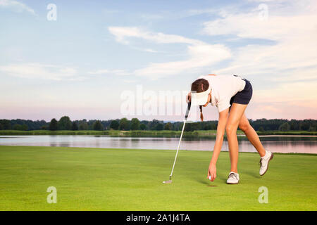 Mädchen golf Player aufnehmen Kugel aus der Schale. Stockfoto