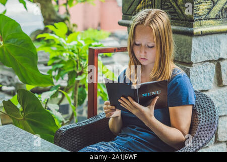 Schöne Frau Bestellungen aus dem Menü im Restaurant und zu entscheiden, was zu Essen. Stockfoto