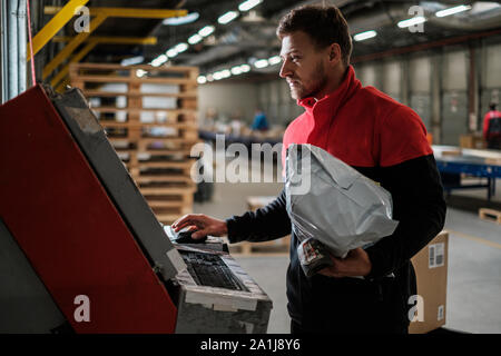 Kurier holt Paket auf einem Lager Stockfoto