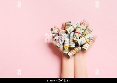 Blick von oben auf die weibliche Hände halten eine Menge aufgerollt Dollar Banknoten auf farbigen Hintergrund. Armut Konzept. Kredit Konzept. Stockfoto