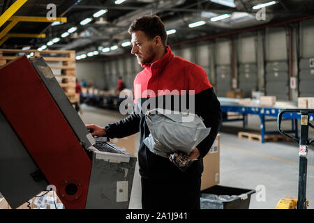 Kurier holt Paket auf einem Lager Stockfoto