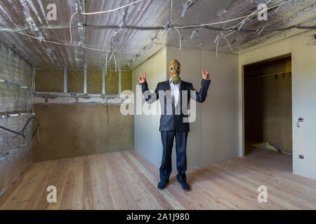 Seltsamer mann Geschäftsmann in Anzug und Gas schutz Maske in einem Raum unter der Renovierungsarbeiten. Stockfoto