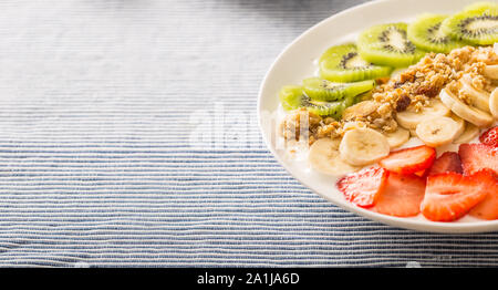 Gesundes Frühstück serviert mit Platte von Joghurt Müsli Kiwi, Erdbeeren und Bananen Stockfoto