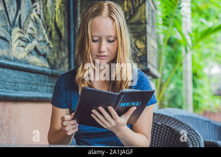 Schöne Frau Bestellungen aus dem Menü im Restaurant und zu entscheiden, was zu Essen. Stockfoto