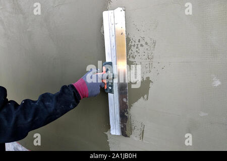 Arbeitnehmer, die isolierte Wand mit Lösung von Klebstoff überputzbar Polystyroldämmung. Stockfoto