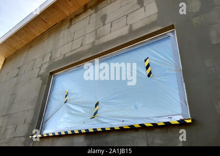 Fenster von einem Haus im Bau mit Schutzfolie abgedeckt. Stockfoto