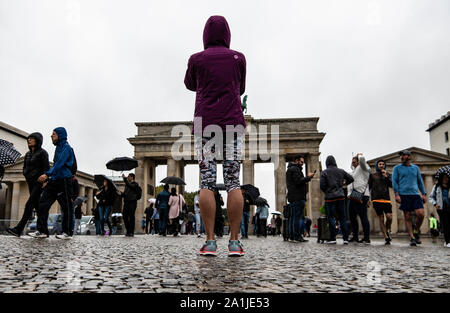 Berlin, Deutschland. 27 Sep, 2019. Eine Läuferin steht im Regen vor dem Brandenburger Tor. Die Frau wird in der Marathon am Sonntag. Credit: Paul Zinken/dpa/Alamy leben Nachrichten Stockfoto