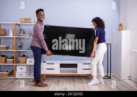 Seitenansicht des jungen Paares Anheben Fernsehen zu Hause Stockfoto