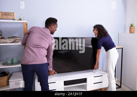 Seitenansicht des jungen Paares Anheben Fernsehen zu Hause Stockfoto