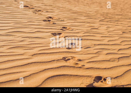 Fußabdrücke im Sand in der roten Wüste bei Sunrise Stockfoto