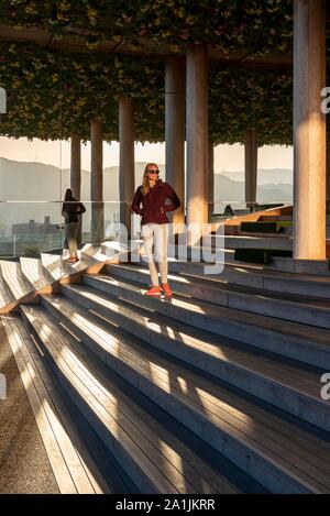 Junge Frau, die auf der Treppe am Panoramadach, Dachterrasse von Hiroshima Orizuru Turm, Hiroshima, Japan Stockfoto