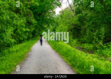 Frau in Hosen und Sneaker zu Fuß nach unten Weg entlang Chesapeake und Ohio Canal Stockfoto