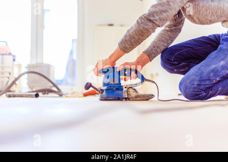 Nahaufnahme eines Sander Elektrowerkzeuge für Heimwerker auf hölzernen Parkettboden Stockfoto