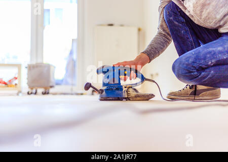 Nahaufnahme eines Sander Elektrowerkzeuge für Heimwerker auf hölzernen Parkettboden Stockfoto