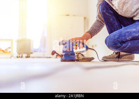 Nahaufnahme eines Sander Elektrowerkzeuge für Heimwerker auf hölzernen Parkettboden Stockfoto