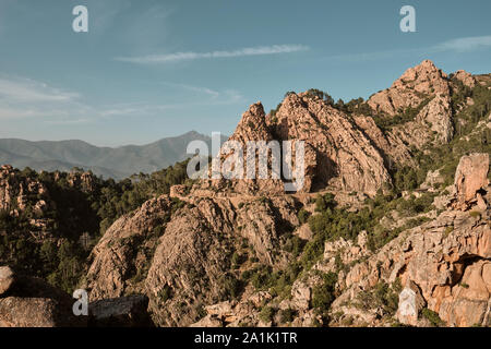 Die roten Felsen und Klippen und Straße entlang der UNESCO Weltkulturerbe Küstenlinie der Calanques de Piana/Golf von Porto im Westen von Korsika. Stockfoto