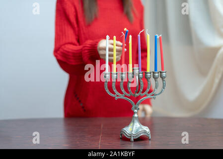 Jüdische Frau Beleuchtung Hanukkah Kerzen in einem MENORAH. Die Menschen feiern Chanukka durch Beleuchtung Kerzen auf der Menora, auch als Hanukiyah. Jede Nacht, eine weitere Kerze angezündet wird. Stockfoto