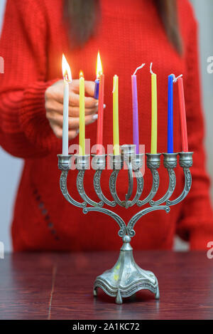 Jüdische Frau Beleuchtung Hanukkah Kerzen in einem MENORAH. Die Menschen feiern Chanukka durch Beleuchtung Kerzen auf der Menora, auch als Hanukiyah. Jede Nacht, eine weitere Kerze angezündet wird. Stockfoto