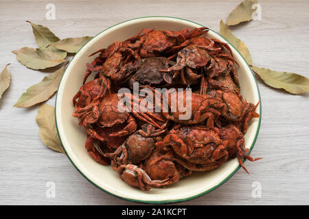 Blaue Krabben in einer Platte auf einem Holztisch und Lorbeerblätter gekocht Stockfoto