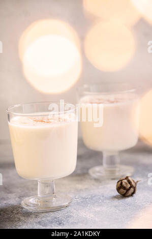 Eierlikör traditionelle hausgemachte Weihnachten und Neues Jahr trinken mit Zimt und Muskatnuss. Winterurlaub Stimmung. Hellen Hintergrund. Selektive konzentrieren. Vertikale Stockfoto