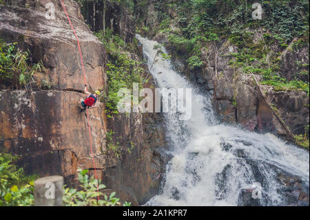 Kletterer im Hintergrund des wunderschönen, kaskadierenden Datanla-Wasserfalls in der Bergstadt Dalat, Vietnam Stockfoto