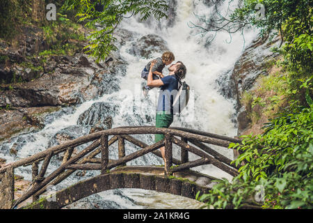 Vater und Sohn im Hintergrund des wunderschönen, kaskadierenden Datanla-Wasserfalls in der Bergstadt Dalat, Vietnam Stockfoto