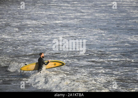 Porthcawl, Wales, UK. Freitag 27. September 2019. Surfer abgebildet in das Meer bei Porthcawl in South Wales, bei Flut am Freitag Abend. Starke Winde aus dem Westen holen in Bands von Heavy Rain und große Wellen zu Beginn des Wochenendes, bei dem die Prognose ist nass und windig wie Herbst Wetter nimmt einen Griff der BRITISCHE machen ideale Surfbedingungen. Credit: Robert Melen/Alamy leben Nachrichten Stockfoto