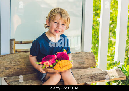 Gewürfelte Drachenfrucht und Mango in den Händen des Jungen Stockfoto