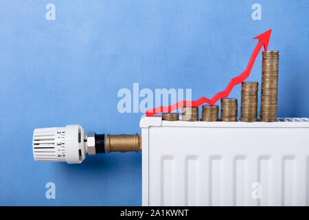 In der Nähe von Pile von Münzen und wachsenden Pfeil auf den Kühler Vor Der Wand Stockfoto