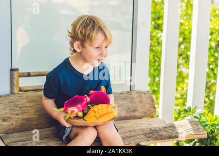 Gewürfelte Drachenfrucht und Mango in den Händen des Jungen Stockfoto