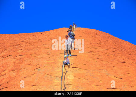 Uluru, Northern Territory, Australien - 23.August 2019: Bergsteiger aufsteigen, Uluru, Kata Tjuta National Park gegen die Wünsche der Aborigines Stockfoto